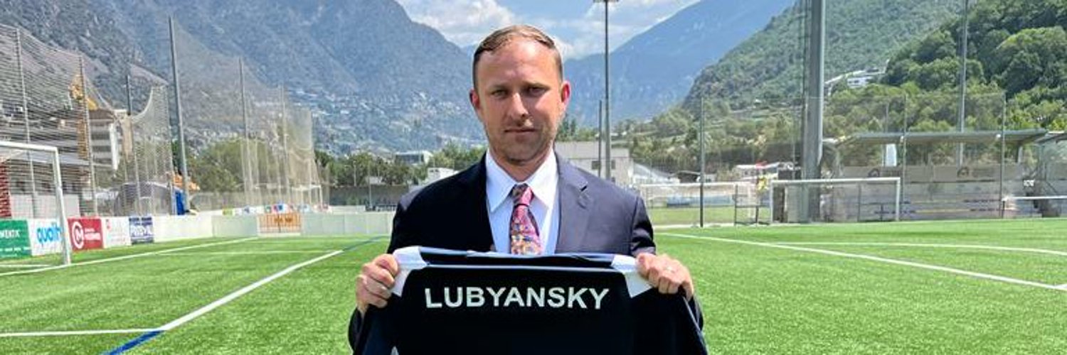 Alex Lubyansky holding a jersey with his name on the back, from his time with FC Santa Coloma